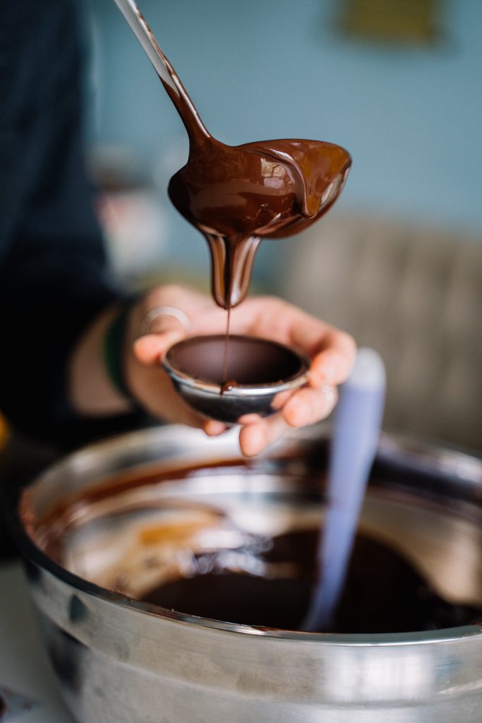 Person pouring melted chocolate into clear cup. (image courtesy of Anna Tarazevich)